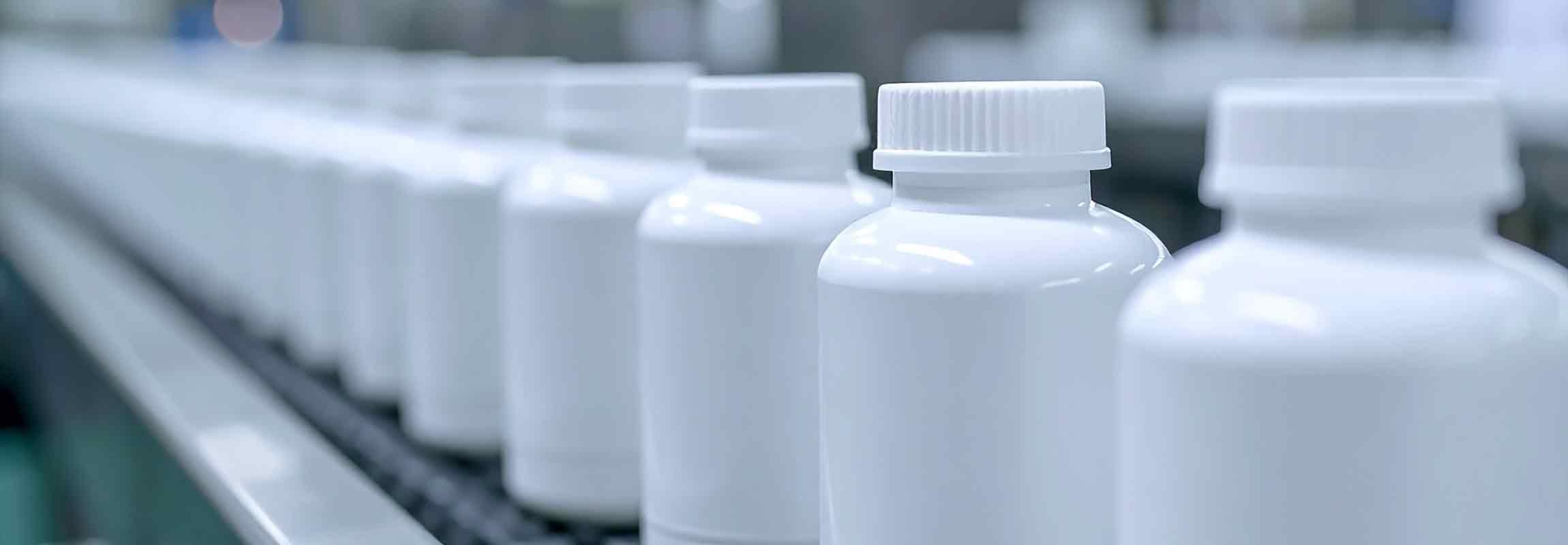 line of white pill bottles on a conveyor belt